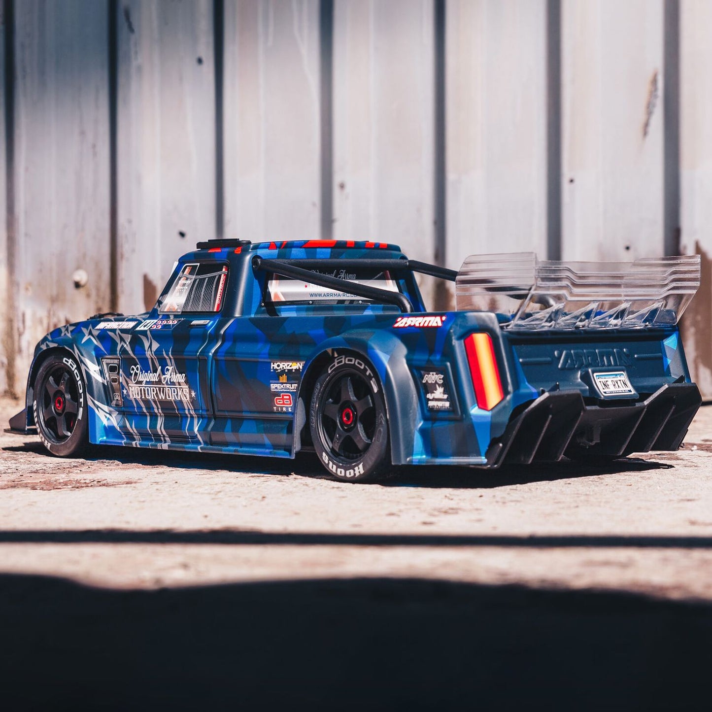 1/7 ARRMA INFRACTION 6S AVC 4X4 RTR - Blue race truck with various sponsor logos on a wooden platform.