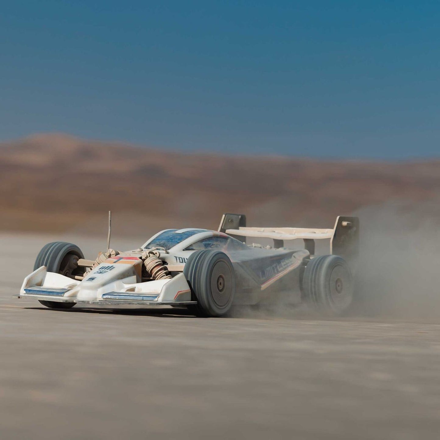 1/7 ARRMA LIMITLESS 120 8S AVC 4X4 RTR - race car driving on a desert track with dust in the air