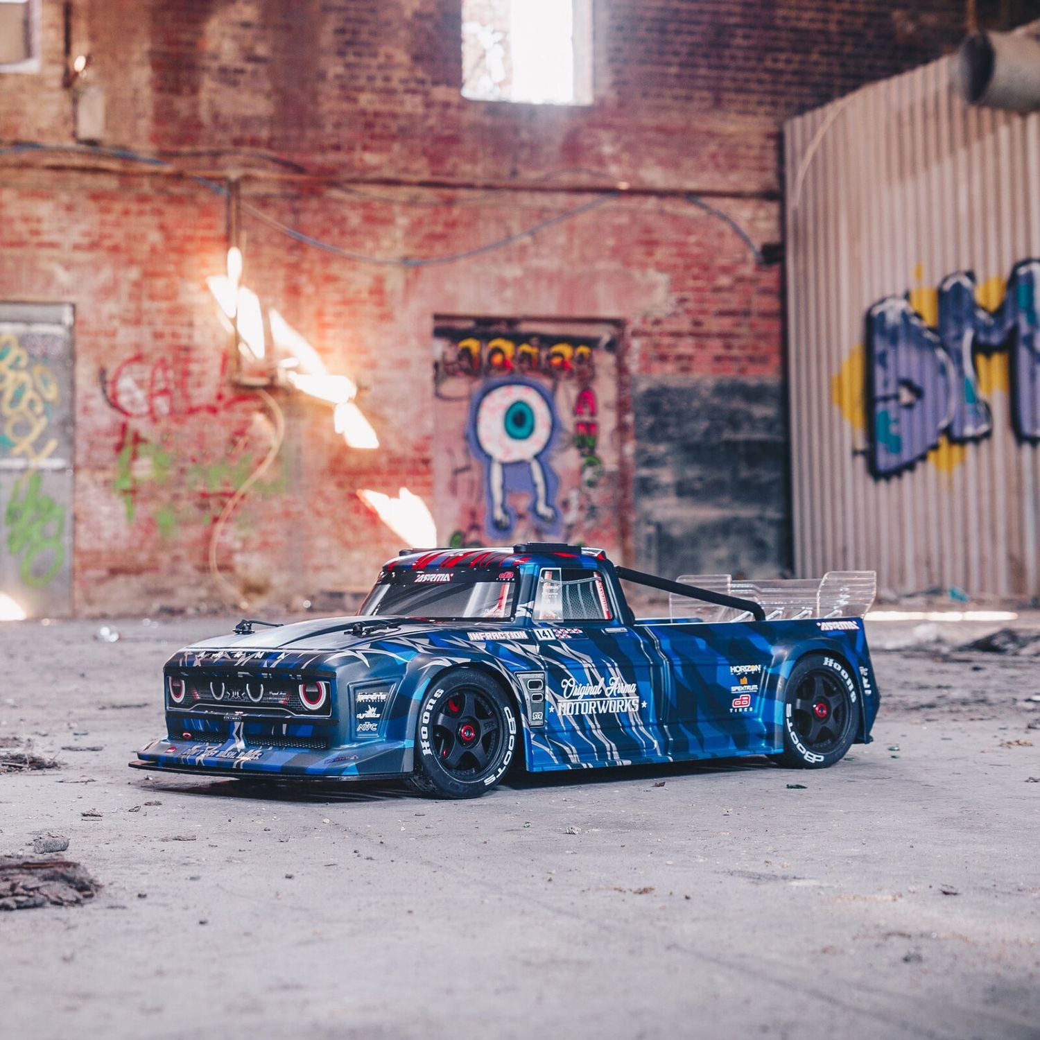 1/7 ARRMA INFRACTION 6S AVC 4X4 RTR - Blue race car in an urban setting with graffiti on the wall