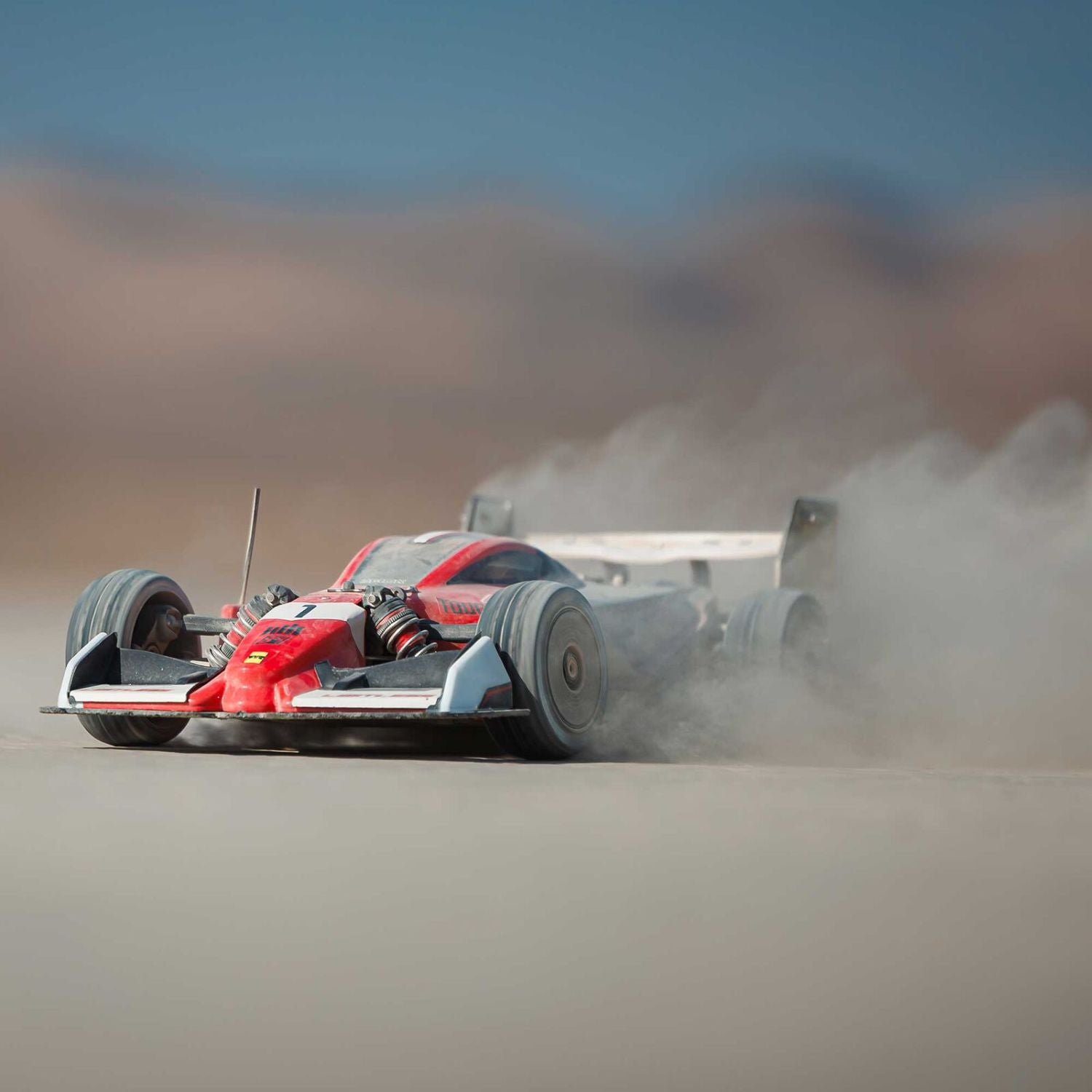 1/7 ARRMA LIMITLESS 120 8S AVC 4X4 RTR - Red and black car racing on a desert track with dust behind it
