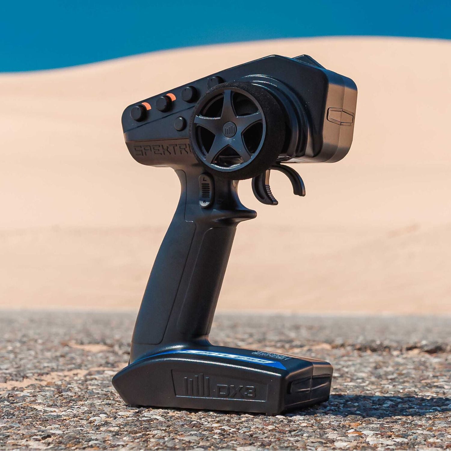 Black Spektrum remote control receiver on a textured surface with a blue sky background